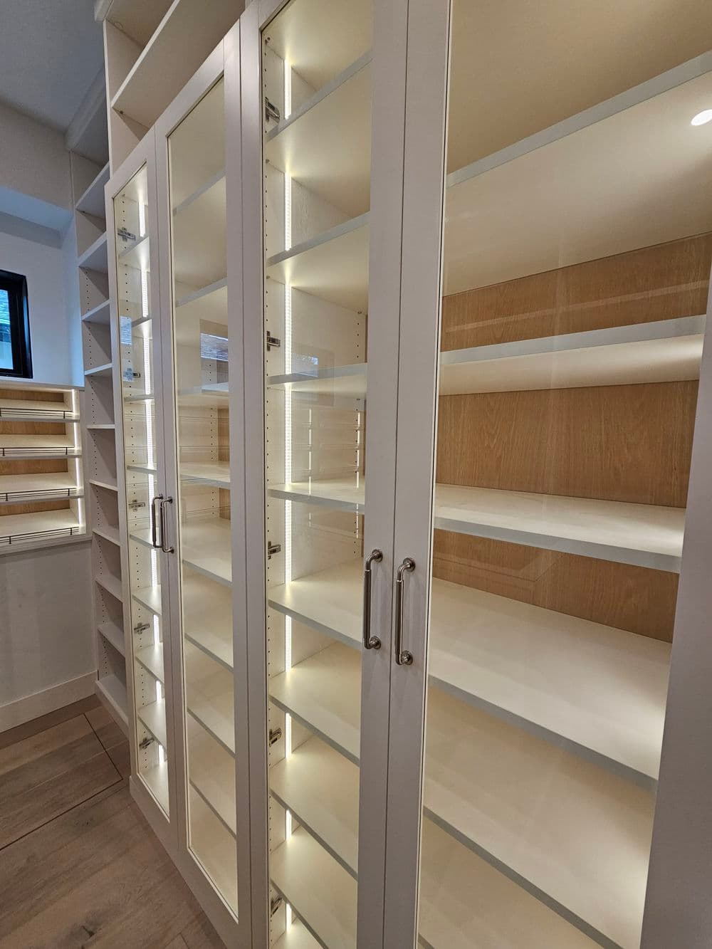 Modern glass display cabinets with bright LED lighting and empty shelving for organization.
