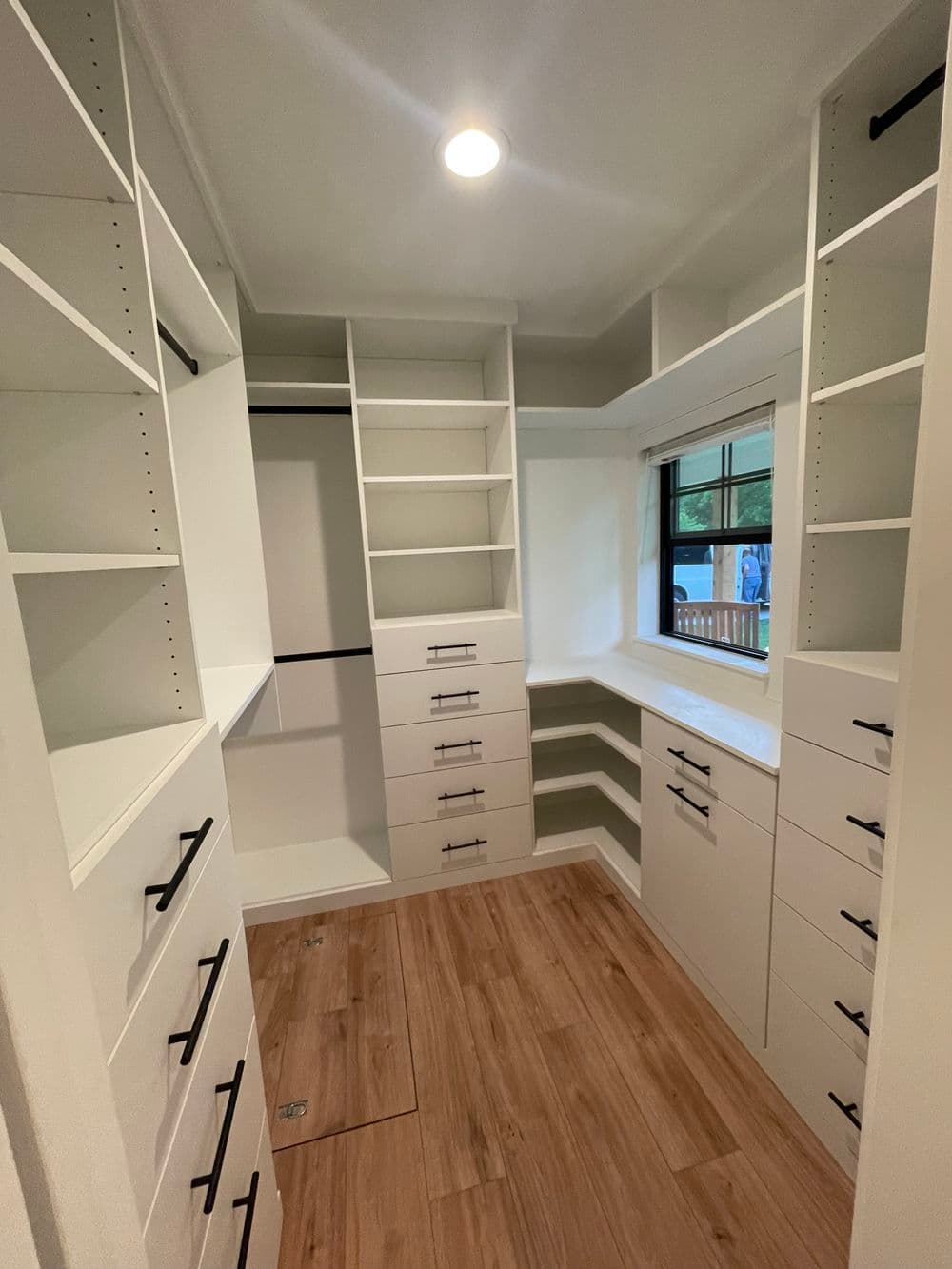 Spacious modern closet design with white shelves and wooden flooring. Ideal for organization.