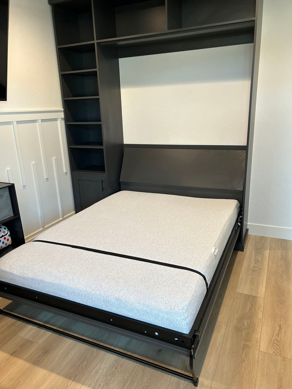Modern queen-sized murphy bed in stylish gray frame, open against a light wall.
