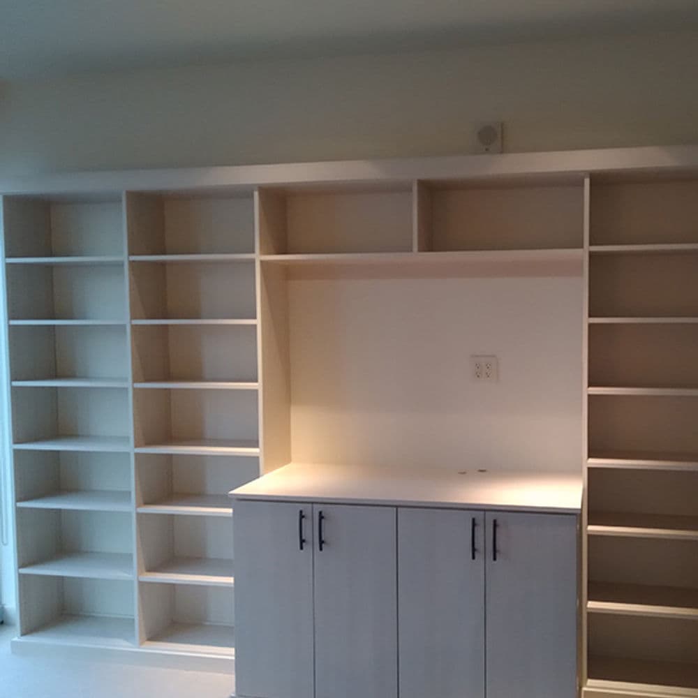 Modern white shelf unit with cabinets and open spaces for books and decor in a styled room.