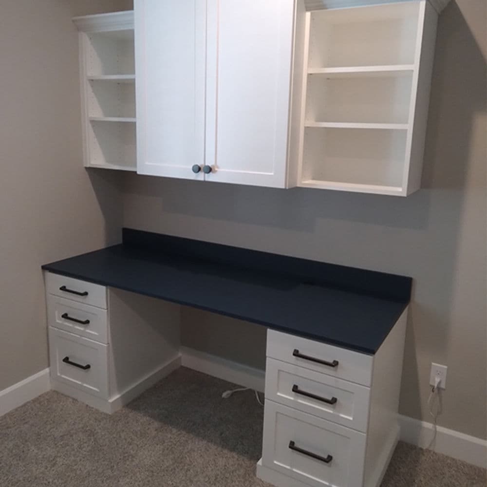 Modern white desk with navy countertop, drawers, and shelving in a minimalist home office.