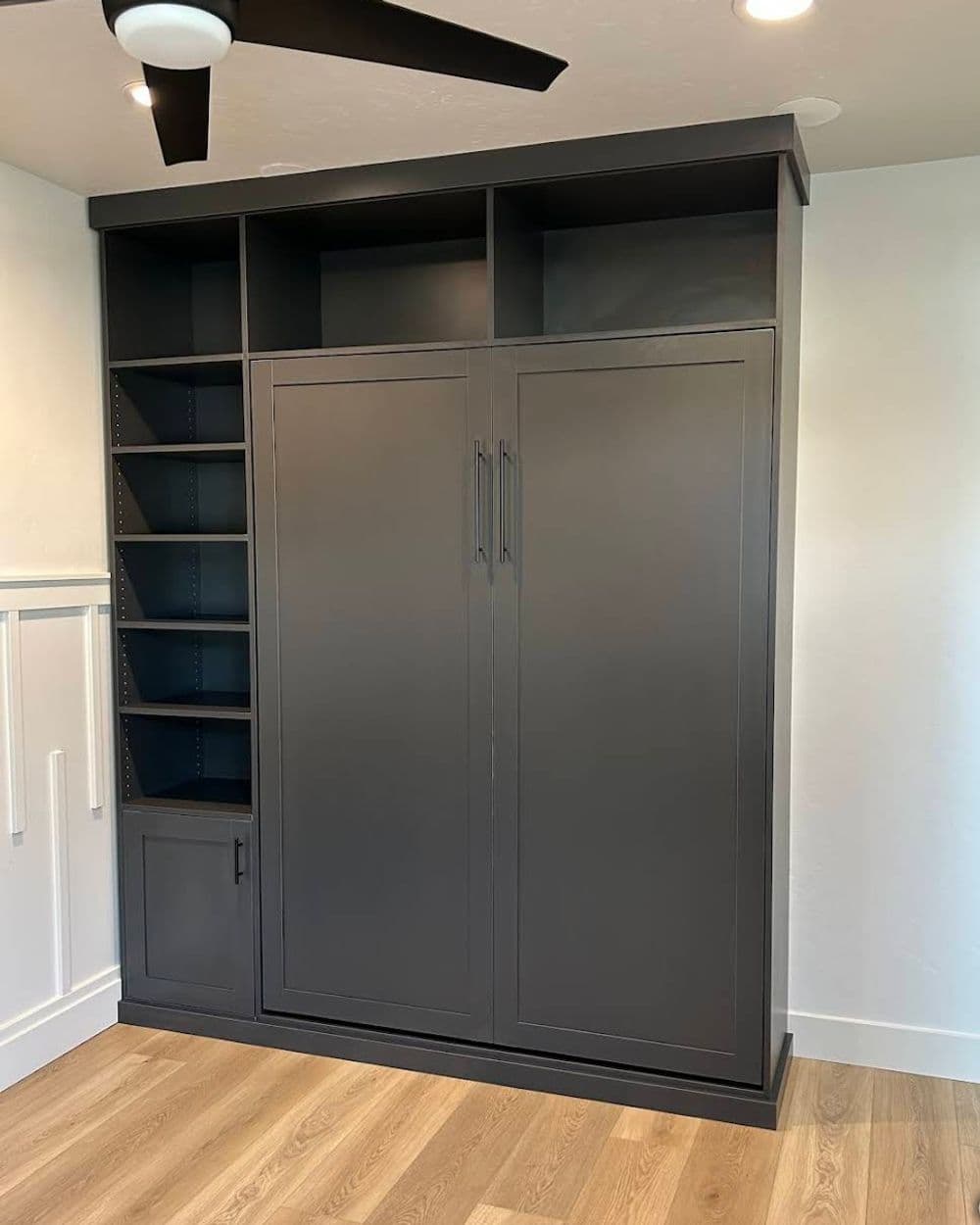 Modern gray cabinet with shelves and closed doors in a bright room. Stylish storage solution.