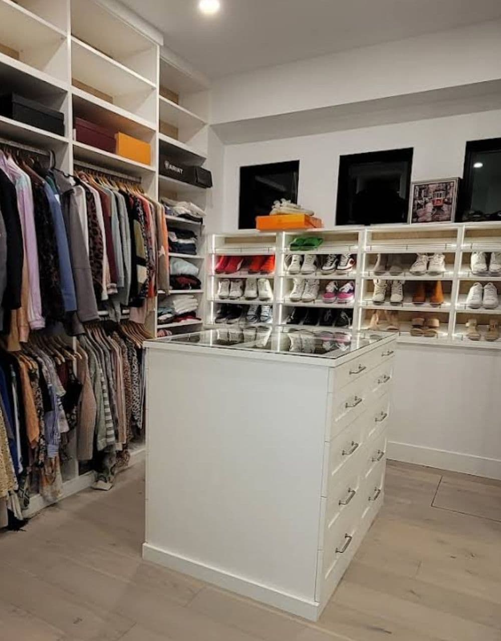 Stylish modern closet with organized clothing racks and shoe display, featuring white cabinetry.