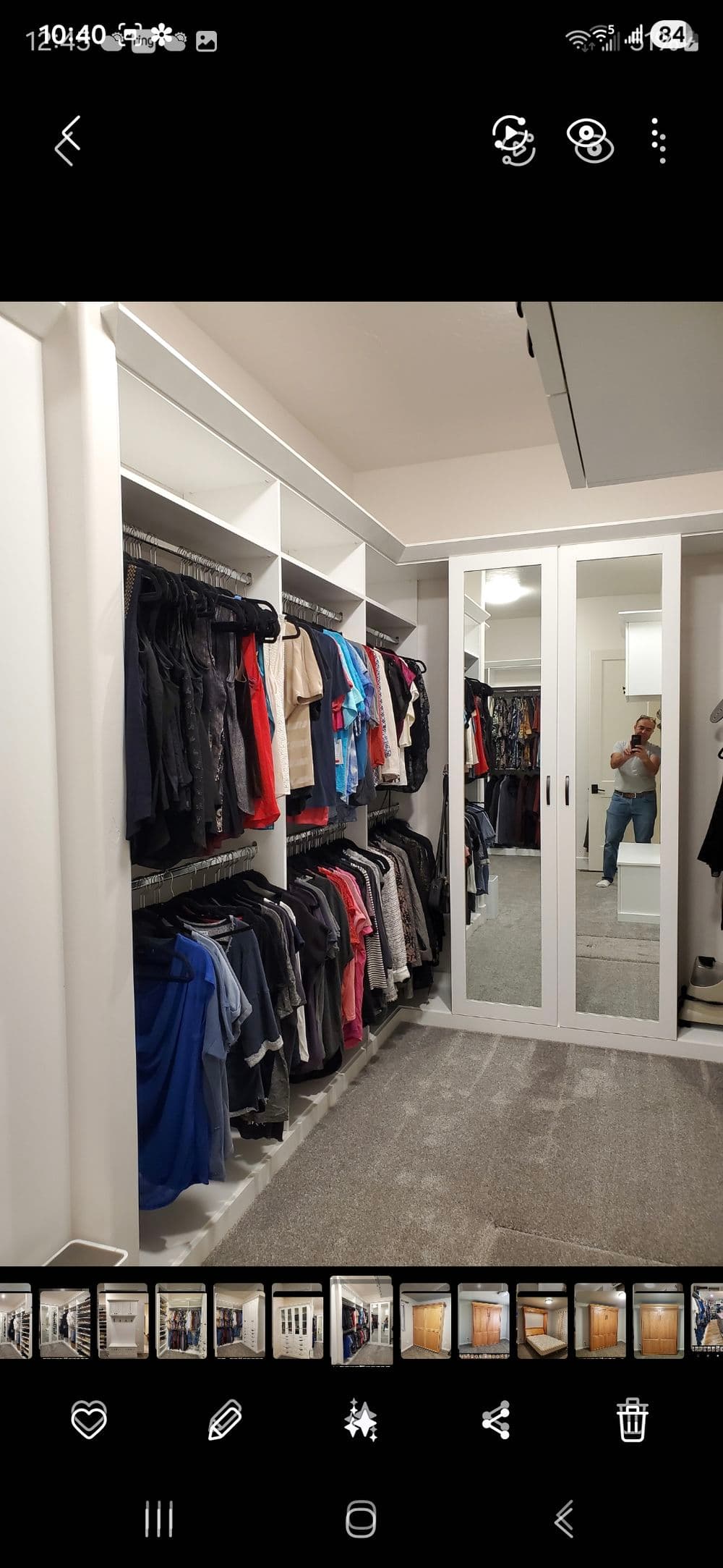 Spacious modern closet featuring organized clothing on racks and mirrored sliding doors.
