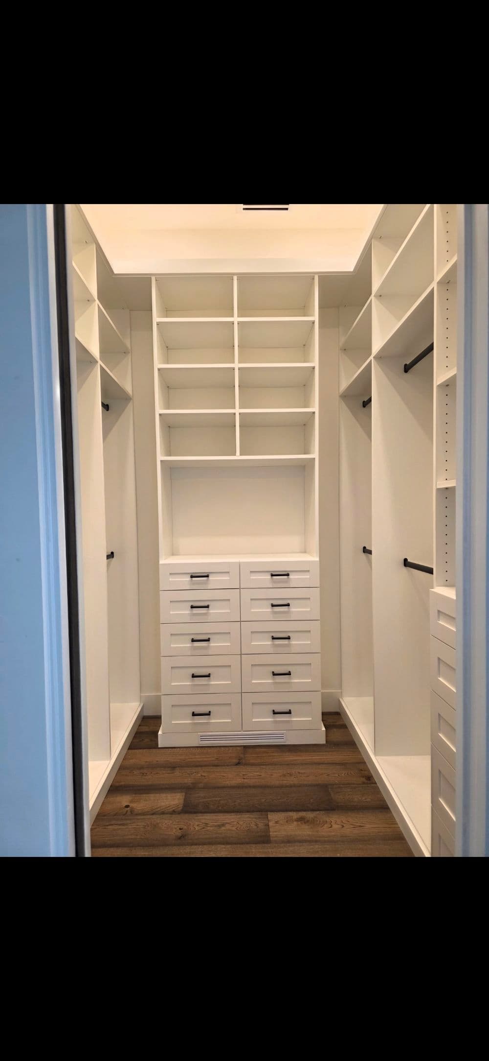 Spacious white walk-in closet with shelves and drawers for organized storage.
