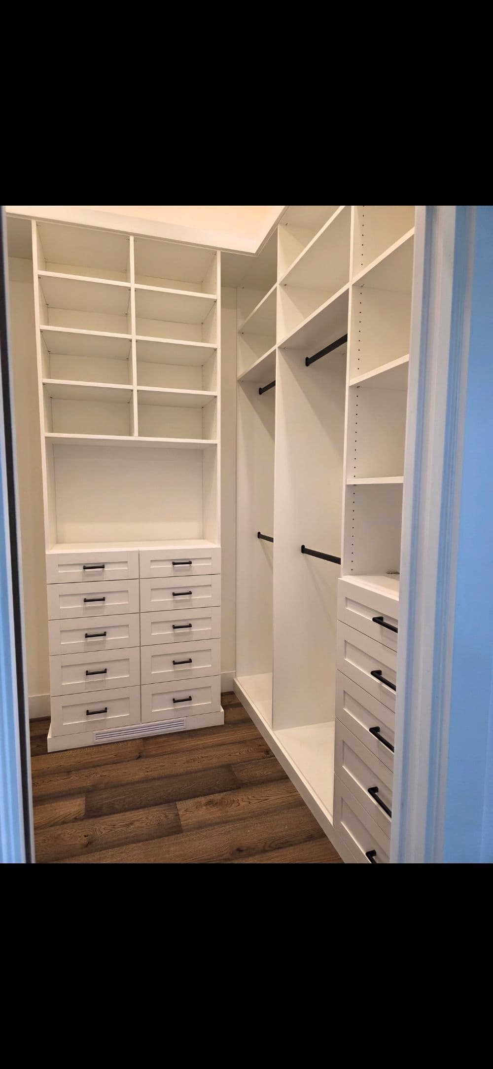 Modern white walk-in closet with shelving and drawers, featuring a minimalist design.