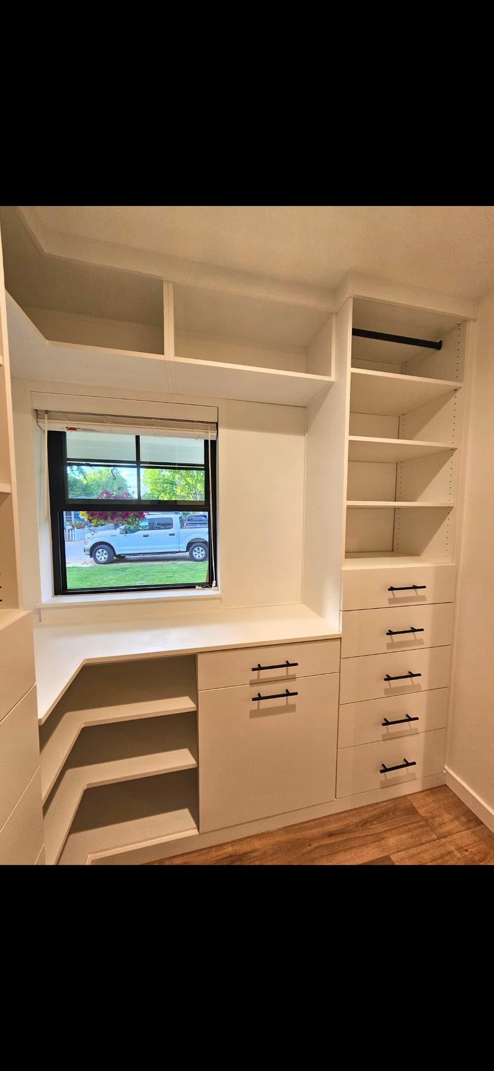 Modern closet design featuring organized shelves and drawers, illuminated by natural light.