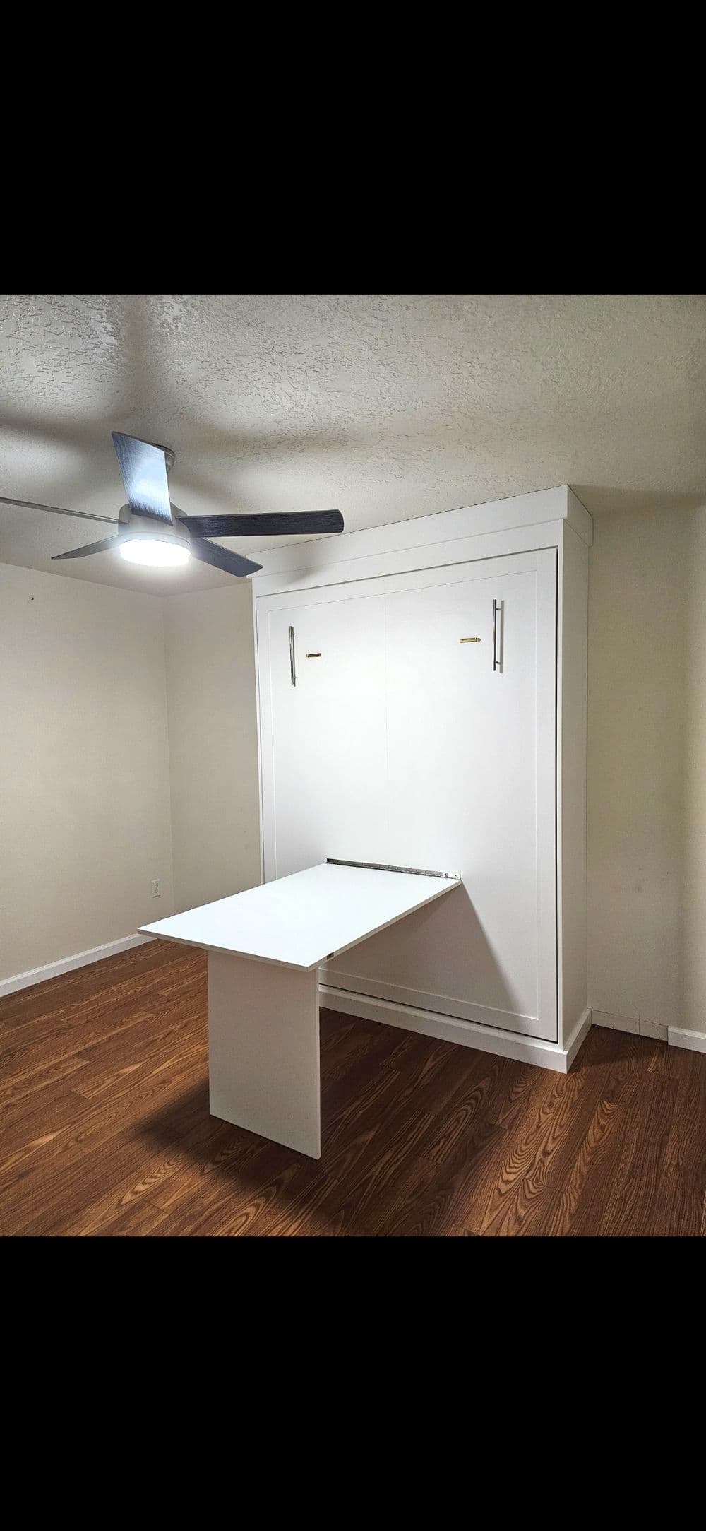 Modern white murphy bed with fold-down table in a minimalist room setting.