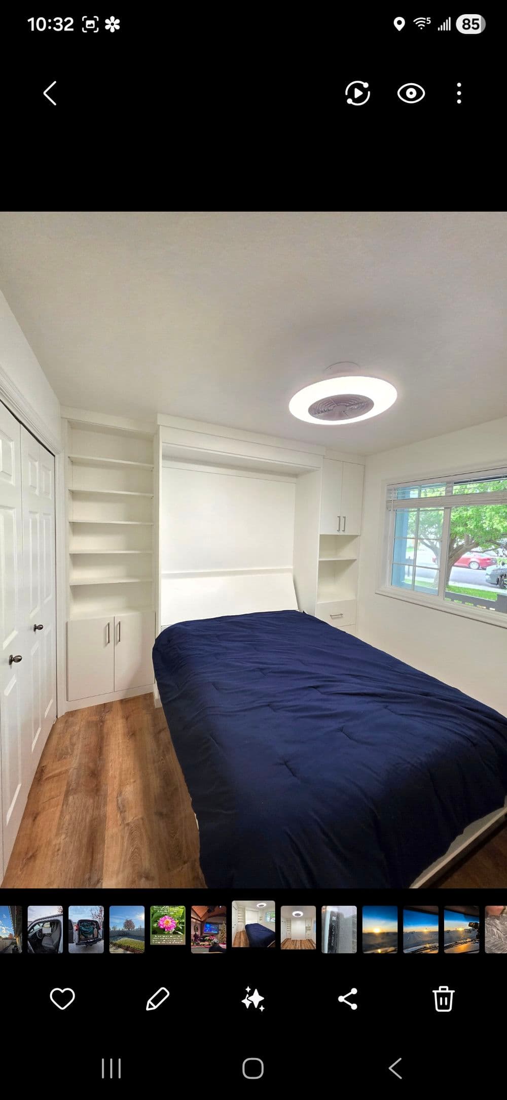 Modern bedroom with a foldable bed, built-in shelving, and large window for natural light.