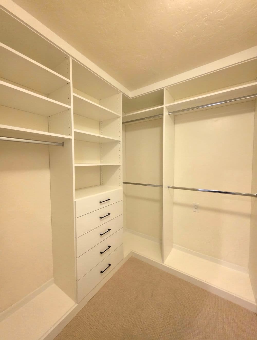 Spacious white closet with built-in shelves and drawers for organized storage.