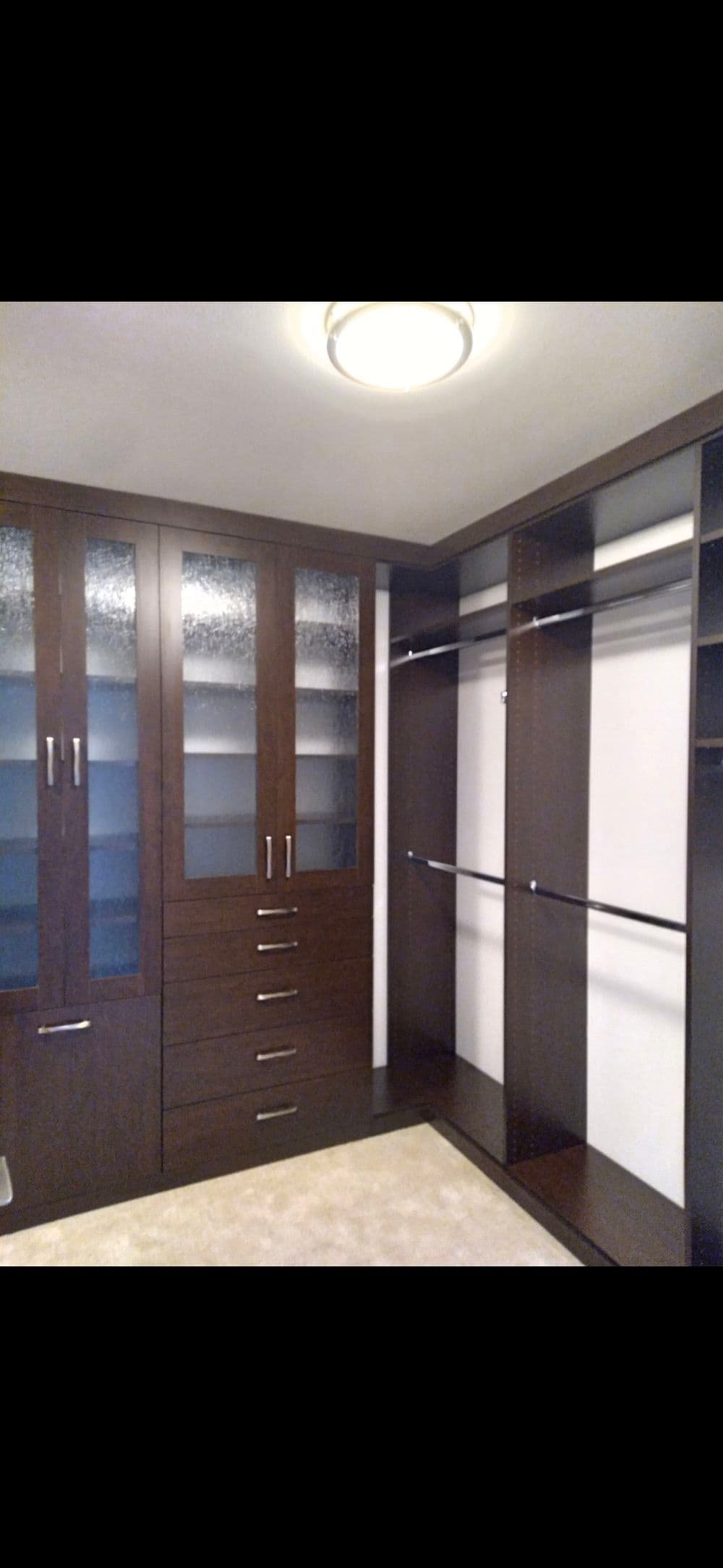 Modern walk-in closet with dark wood cabinetry, shelves, and organizing drawers.