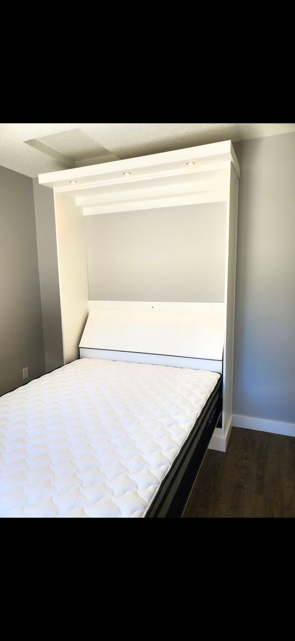 Modern foldable wall bed with white frame and mattress, ideal for space-saving solutions.