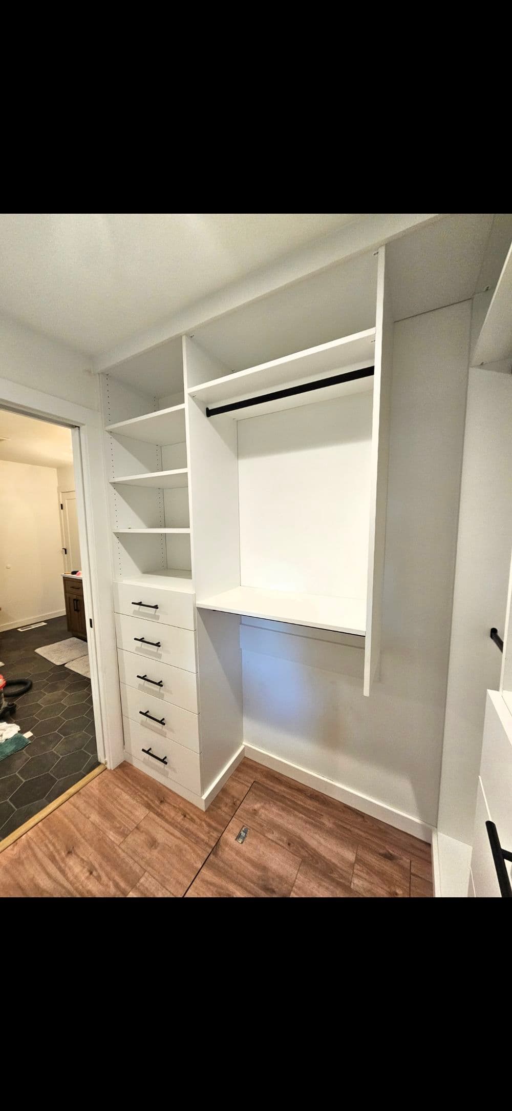 Modern closet interior with white shelving, drawers, and hanging space for organization.